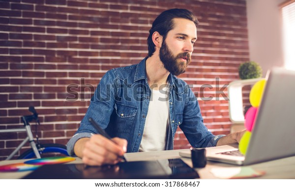 Creative businessman writing on graphic tablet
while using laptop in
office