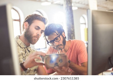 Creative businessmen reviewing proofs at computers in sunny office - Powered by Shutterstock