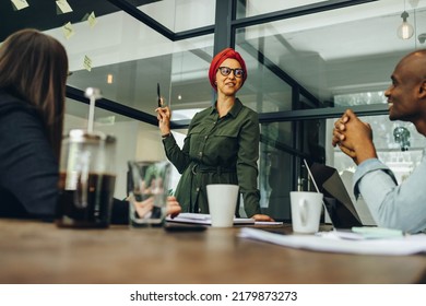 Creative Businesswoman Sharing Her Ideas With Her Team During A Meeting. Muslim Businesswoman Leading A Discussion In A Boardroom. Team Leader Wearing A Headscarf In A Multicultural Workplace.