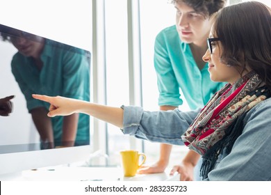 Creative Businesswoman Showing Something To Colleague On Desktop Computer In Office