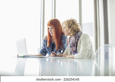 Creative businesswomen working on laptop together in office - Shutterstock ID 226254145