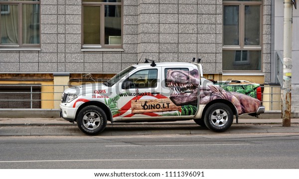 Creative car with a dinosaur\
picture. Entertainment and advertising business in Lithuania.\
Modern urban cityscape. Baltic countries. Lithuania, Vilnius -\
April 27, 2017