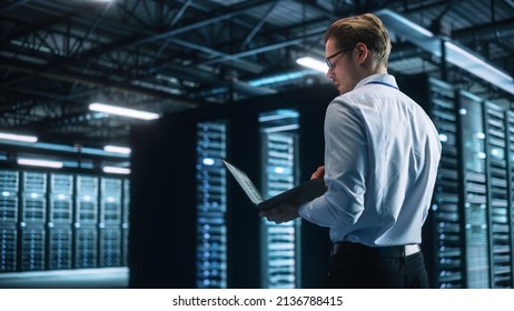 Creative Caucasian Man Using a Laptop Computer in Evening Office. Independent Businessman is Walking Through the Office and Looking Away. Technology Science Breakethrough, Progress, Innovation Concept