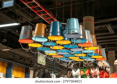 Creative ceiling light installation made of colorful upside-down metal buckets in a modern store interior.