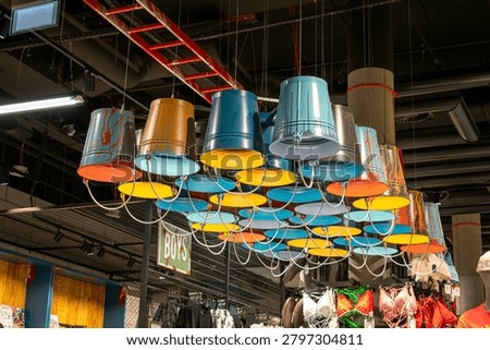 Creative ceiling light installation made of colorful upside-down metal buckets in a modern store interior.