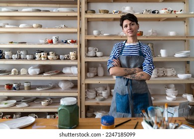 Creative ceramics studio owner at workplace standing arms crossed and looking at camera. Confident entrepreneur crafts woman in pottery studio preparing for master class or work process - Powered by Shutterstock