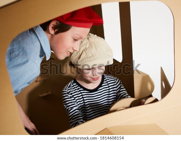 Creative\
children plays in cardboard car\
playhouse.