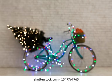 Creative Christmas blue bicycle with pine tree and gifts wrapping in lights, copy space, blurred background