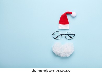 Creative Christmas Composition. Greeting Card, Invitation Or Flyer. Santa Hat, Beard And Glasses On Blue Background Top View. Flat Lay. 