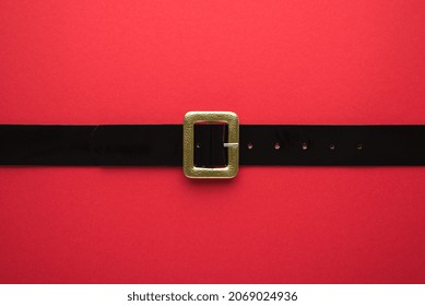 Creative Christmas composition. Overhead flat lay view photo of Santa Claus black belt with golden buckle on bright color red backdrop