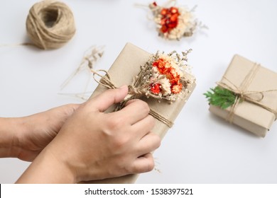 Creative Christmas Craft Handmade Hobby. Woman Hands Decorating Presents With Dried Flower And Pine Leaves For Christmas, New Year Or Other Anniversary Gift Boxes.