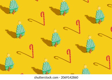 Creative Christmas pattern made with pine trees and candy canes on vivid yellow background. Minimal Xmas or New Year eve celebration concept. Minimal winter holidays idea. Contemporary wallpaper.