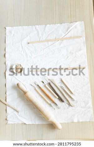 Creative clay pot on worktable with wooden handles and cloth, top-down perspective, gray and white tones, artistic and serene mood, crafting and pottery context.