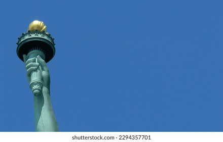 Creative closeup of only arm of Statue of Liberty, New York, USA isolated against clear, deep blue, cloudless, summer sky. Copy space.
