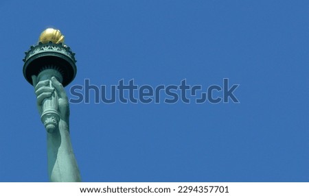 Creative closeup of only arm of Statue of Liberty, New York, USA isolated against clear, deep blue, cloudless, summer sky. Copy space.