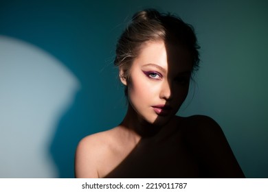Retrato creativo de una bella muchacha con un delineador de ojos parado en el escenario con un rayo de luz brillante