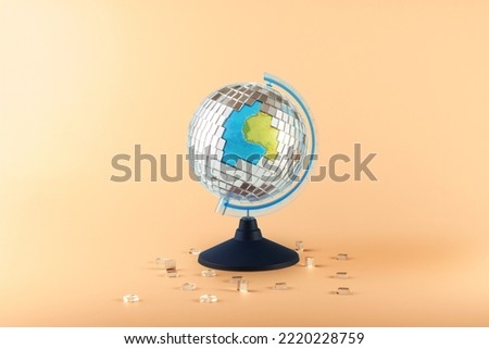 Creative collage of a globe and a scattering disco ball on an orange background. 