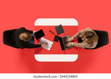 Creative collage. Two young women sit at common table with documents and conduct interview against red studio background. Concept of business, work, job, meeting, office. Copy space. Ad - Powered by Shutterstock