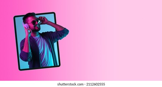 Creative Colorful Collage. Cherful Amn Listening To Music In Headphones Sticking Out Laptop Screen Isolated Over Pink Background. Youth Culture. Concept Of Lifestyle, Online Communication And Ad