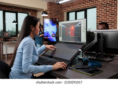 Creative company game developer sitting in production department while developing 3D videogames scenes and environment. Asian employee working on level design using modern software.