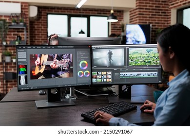Creative company professional movie footage editor sitting at multi monitor workstation while editing film frames. Expert videographer improving video quality using specialized software. - Shutterstock ID 2150291067