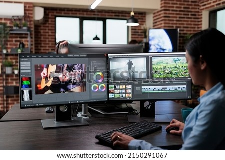 Creative company professional movie footage editor sitting at multi monitor workstation while editing film frames. Expert videographer improving video quality using specialized software.