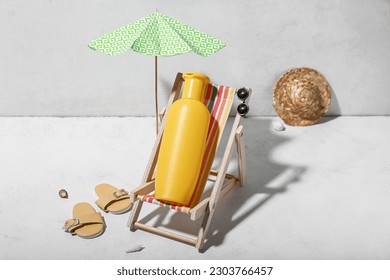 Creative composition with beach accessories and sunscreen on white table near wall
