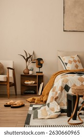 Creative composition of bedroom interior with bed, beige and orange bedding, plaid, patterned rug, red armchair, black rack, wooden bedside table and personal accessories. Home decor. Template.