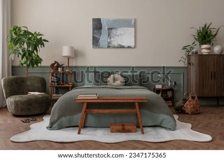 Creative composition of bedroom interior with mock up poster frame, green bedding, wooden side table, stylish bench, beige rug, plants, basket, lamp and personal accessories. Home decor. Template. 

