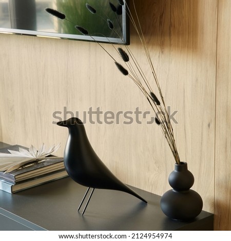 Creative composition of details of modern living room interior in small apartment Black commode, figure of black bird, tv and personal accessories. Template.
