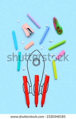 Creative composition with drawn rocket and different stationery on blue background