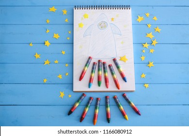 Creative composition with drawn rocket in notebook on color wooden background