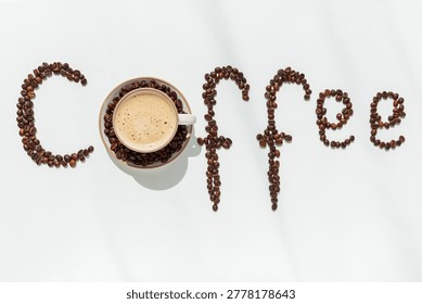 Creative composition featuring coffee beans arranged to spell the word “Coffee,” with the first letter formed by a cup of frothy coffee completing the circular shape. 