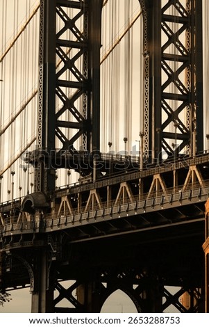 A creative composition featuring the Empire State Building perfectly framed through the arch of the Manhattan Bridge, capturing iconic New York architecture at sunset.