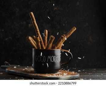 Creative composition. Fragrant cinnamon sticks in a black cup on a table against a dark background. Spices, aromatic additives, ingredient for different dishes. Cooking, medicine. - Powered by Shutterstock