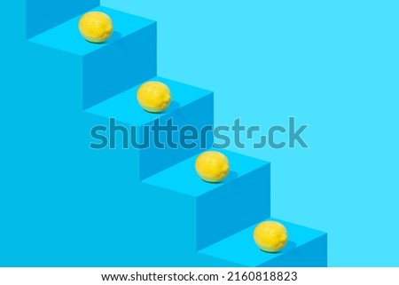 Creative composition with fresh yellow lemons on blue staircase. Creative copy space. Next level concept.