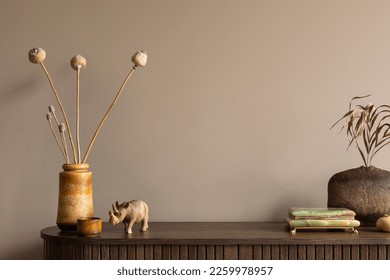 Creative composition of living room interior with wooden sideboard, stylish vase with dried flowers, stylish casket, nuts in bowl, brown wall and personal accessories. Home decor. Template. 