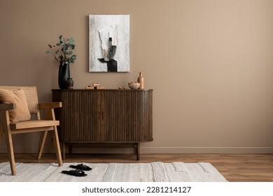 Creative composition of living room interior with mock up poster frame, copy space, wooden sideboard, vase with branch, rattan armchair, beige rug and personal accessories. Home decor. Template. 