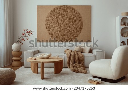 Creative composition of living room interior with mock up poster frame, beige sofa, wooden coffee table, rounded shapes armchair, vase with rowanberry and personal accessories. Home decor. Template.