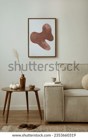 Creative composition of living room interior with mock up poster frame, modern beige sofa, oval wooden coffee table,  round pillow, glass case, creative bowl with dried fruit, sculpture. Home decor. 
