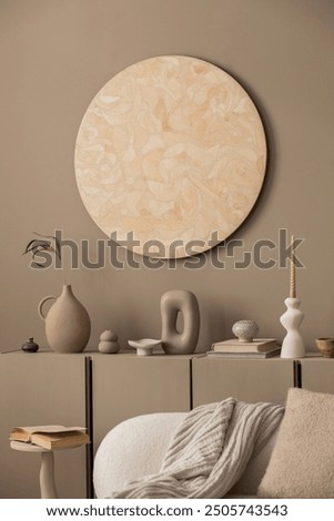 Creative composition of living room interior with round wall panel, brown sideboard, stylish coffee table, vase with dried flowers, beige sofa, pillows and personal accessories. Home decor. Template.