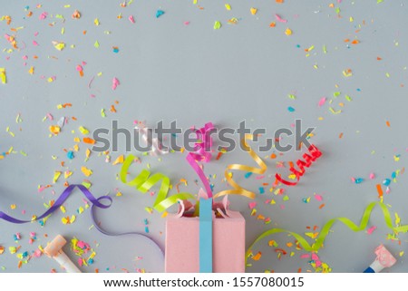 Creative composition made with gift box and party streamers on pastel grey background. Celebration party flat lay concept.