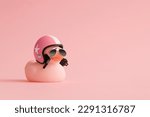 Creative composition made of pink cute little rubber duckling with a helmet and sunglasses on pink background.Summer minimal duck concept. Creative art, Contemporary style.Writing space, copy space.