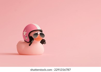 Creative composition made of pink cute little rubber duckling with a helmet and sunglasses on pink background.Summer minimal duck concept. Creative art, Contemporary style.Writing space, copy space.