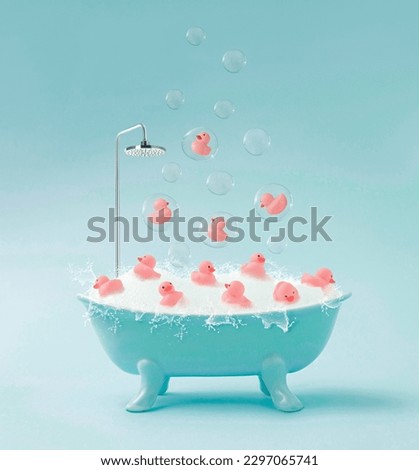 Creative composition made of pink cute little rubber ducklings they swim in bathtub full of soapy water and floating in a soap bubbles.Contemporary style.Creative art minimal aesthetic.minimal concept