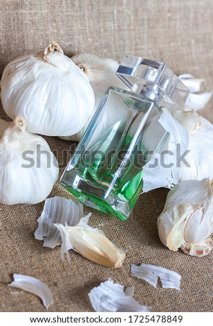 Creative composition perfume and garlic lie on a natural homespun napkin, the concept of combining incompatible things and objects, an oxymoron, power clashing, copy space for text, selective focus