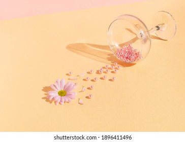 Creative composition with pink pearls and flower spilling out of champagne glass on bright peach puff background. Minimal spring love concept. - Shutterstock ID 1896411496