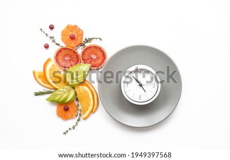 Creative composition with plate, clock (alarm clock) and sliced fruits. Diet and nutrition concept