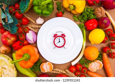 Creative composition with red clock on the white plate with colorful vegetables. Paprika, onion, garlic, tomato, cherry. Time for healthy food. - Shutterstock ID 1239351241