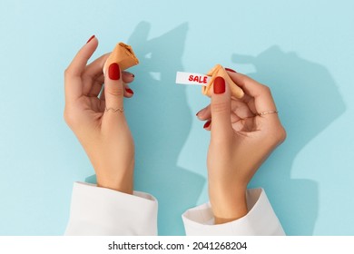 Creative composition for shopping sale. Women hands with manicure holding fortune cookie